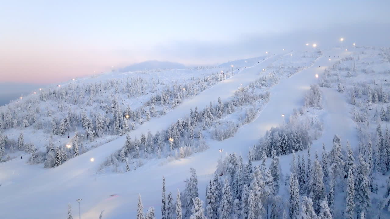 Aerial orbit shot overlooking the snowy slopes of Sallatunturi, dawn in Finland