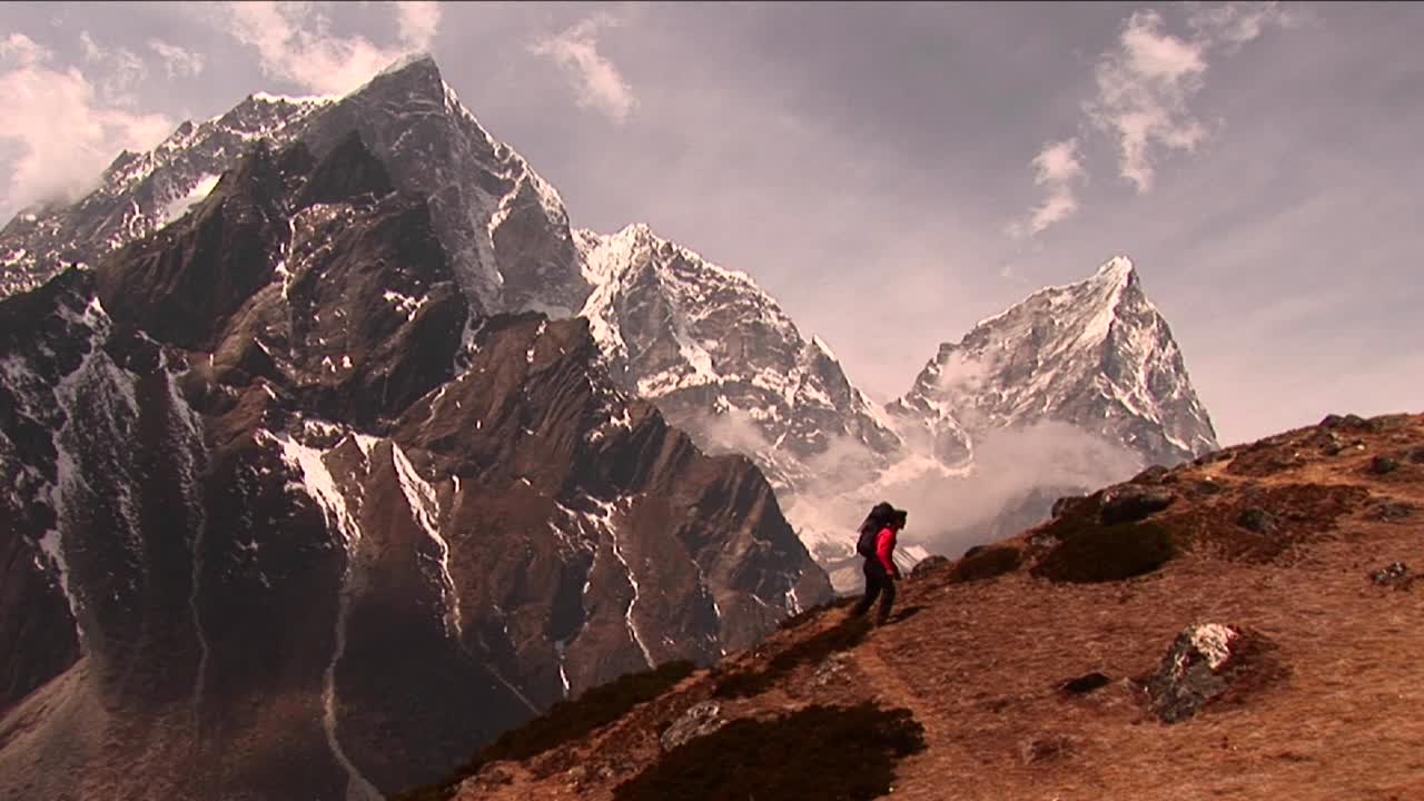 trekker subiendo una colina empinada con un gran pico en la espalda