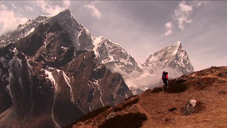 trekker climbing steep hill with large peak in back