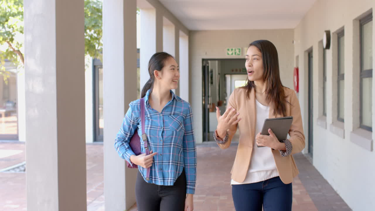 Teenage Asian girl chats with a young biracial woman at high school