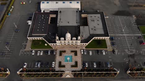 drone 4k of front facade of sikh temple with beautiful and elaborate sculpture and symmetrical architecture revealing the blueberry farmland and parking lots around the building