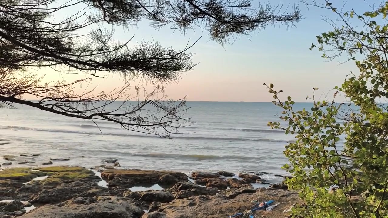 Vista serena di onde del mare che si infrangono su una costa rocciosa al tramonto