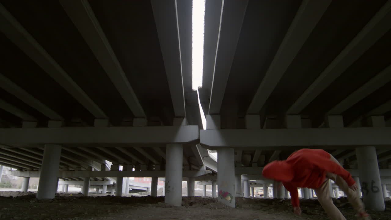 Parkourist Performing Trick under Urban Bridge