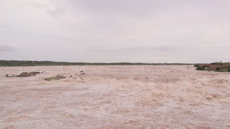 Village,-trees-and-small-hills-submerged-in-Flood-due-to-heavy-rain-causing-heavy-water-flow-from-the-reservoir-in-North-Karnataka,-India