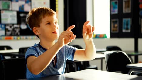 Schoolboy-pretending-to-touch-an-invisible-screen-in-classroom-4k