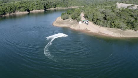 Tire-Hacia-Atrás-De-La-Vista-Aérea-Ascendente-De-Un-Jet-Ski-Dando-Vueltas-En-Círculos-En-Un-Lago-Tropical