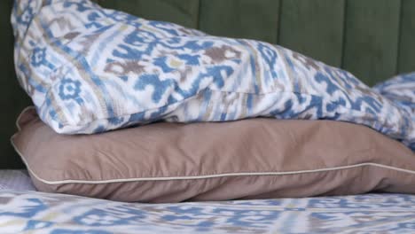 close up of a brown pillow on a bed with a blue and white patterned bedspread