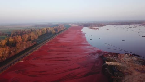 Uninterrupted-aerial-view-of-drone-gliding-forwards-of-the-red-mud-or-red-lake,-toxic-sludge-deposits-in-Stade,-Lower-Saxony,-Germany
