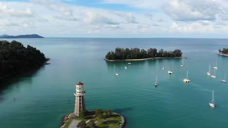 Aerial-Orbit-View-Of-A-Lighthouse-At-A-Harbour-With-Turquoise-Ocean-And-Boats