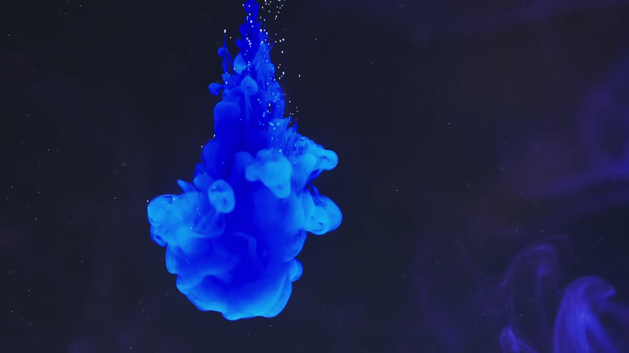 замедленное видео синего акварельного чернила, смешивающегося с водой на черном фоне