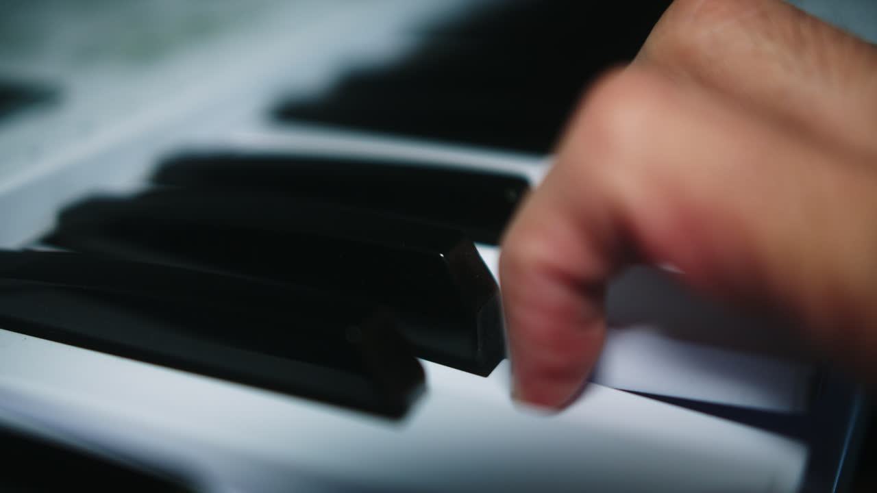 Amazing slow motion shot of a young professional male musician playing chords on the piano with two hands inside his home studio recording a song.