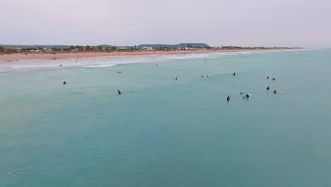 Los-Surfistas-De-Longboard-Esperan,-Flotan-En-El-Agua-Al-Atardecer-En-La-Playa-Del-Palmar-España