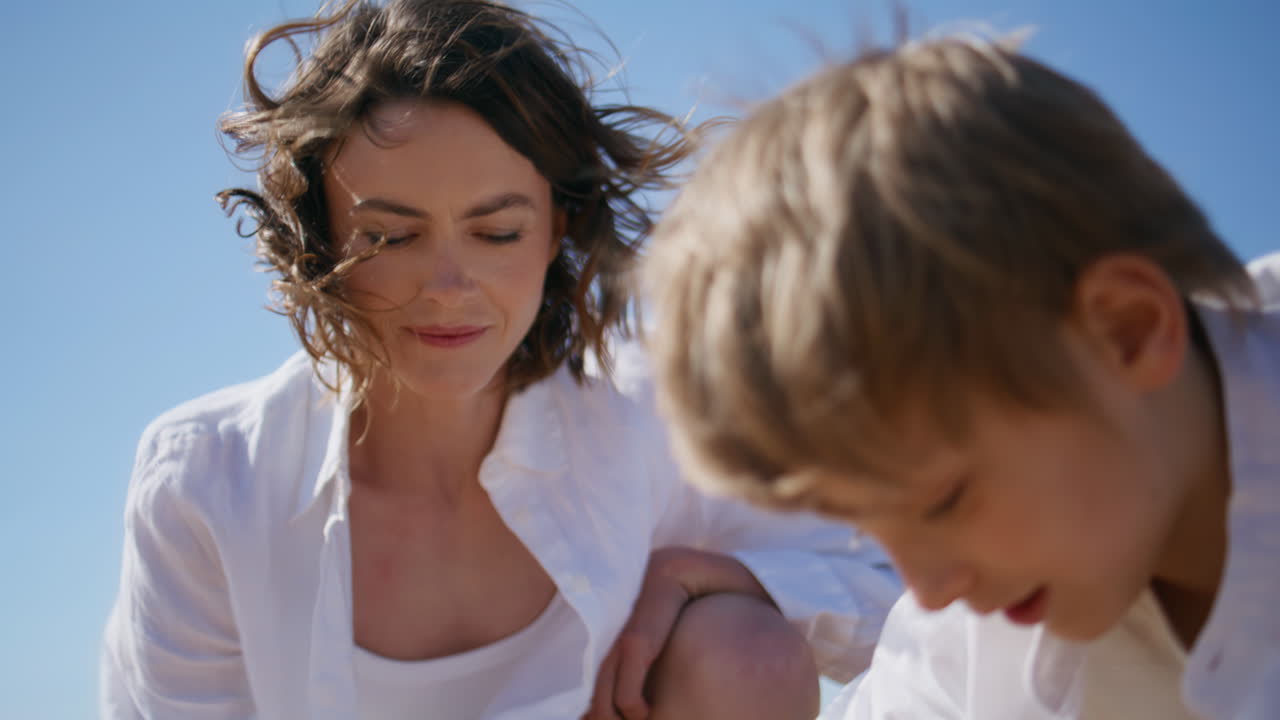 Caring woman playing child at summer beach closeup. Happy mother boy drawing