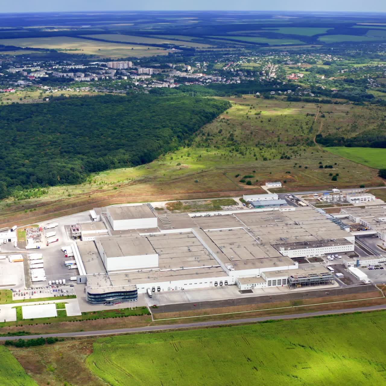 Modern plant in the countryside. Industry among beautiful green nature. Factory in environment in summer. Aerial view