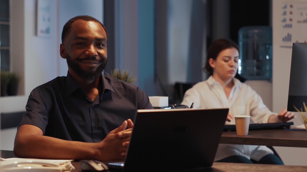 Portrait of happy successful manager sitting at desk at night