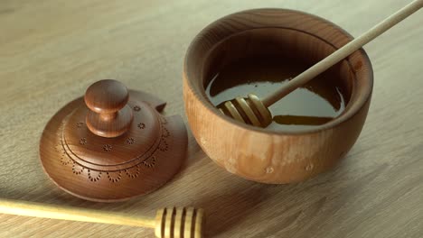 Honey-dripping,-pouring-from-honey-dipper-in-wooden-bowl.-Close-up.-Healthy-organic-Thick-honey-dipping-from-the-wooden-honey-spoon,-closeup.-4K-UHD-video-footage.-Slow-motion