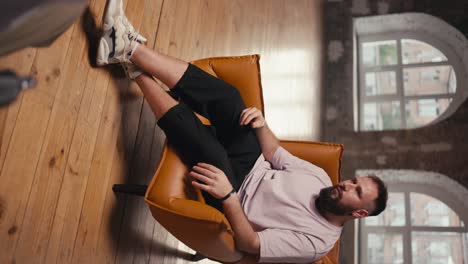 Vertical-video-of-a-man-with-a-beard-expressively-talking-about-his-problem-to-a-psychologist-during-therapy.-Man-in-a-pink-T-shirt-and-black-shorts-In-therapy-with-a-psychologist