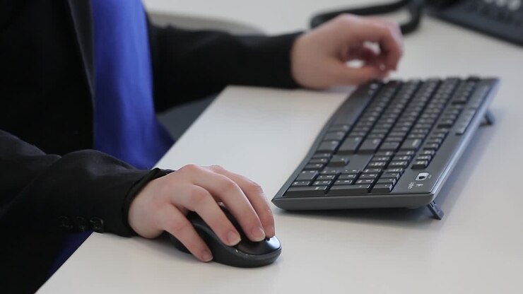 Primo piano di una donna che si prepara a usare mouse e tastiera a un computer.