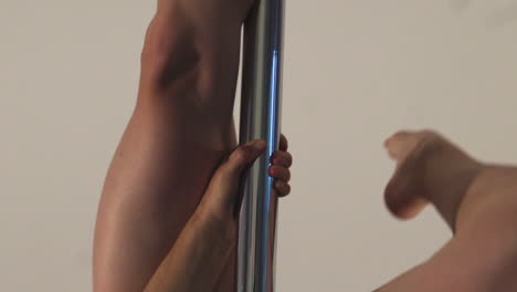 female pole dancer swinging her feet up towards the pole, hanging upside down in slowmotion