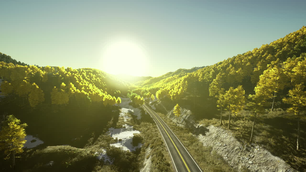 Sunrise over winding road through vibrant autumn forest in mountainous region