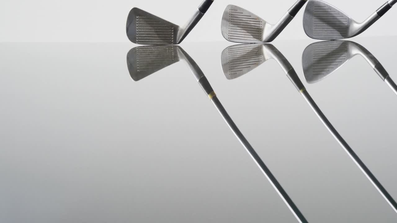 Close-up van golfclubs op witte achtergrond, met ruimte voor tekst, in slow motion.