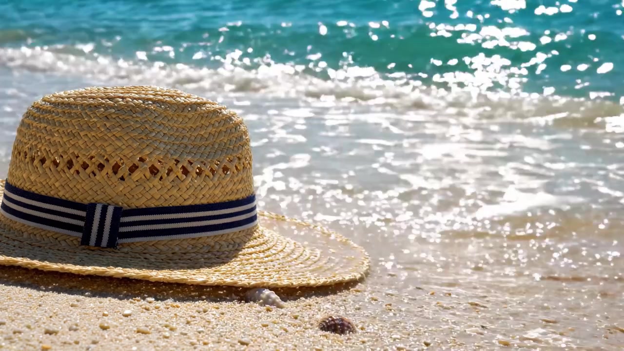 Un cappello di paglia da sole che riposa sulla riva di una spiaggia, circondato da onde leggere e sabbia scintillante, catturando l'essenza di una perfetta giornata estiva al mare
