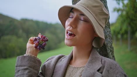 woman eating grapes in a vineyard on a rainy day