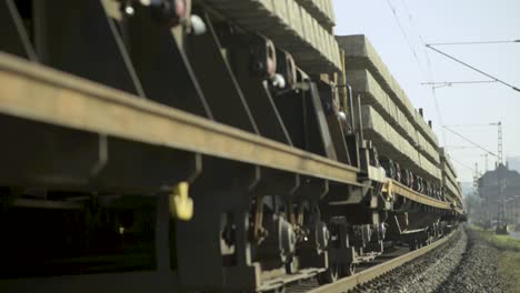 railroad freight train loaded with industrial materials moving along tracks, sunny day