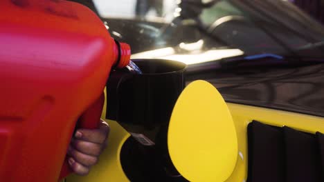 pouring fuel from the canister into the yellow german super sport car