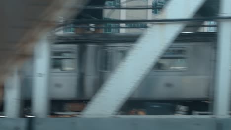 Looking-out-the-window-of-a-New-York-City-subway-train-in-motion-seeing-another-train-going-over-the-Manhattan-Bridge-with-the-skyline-in-the-background