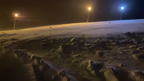 wind is blowing snow on a top of a ski slope during a dark winter day in northern scandinavia