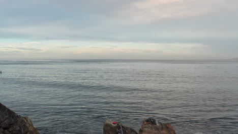 flyover of a woman on the beach and then towards the endless ocean horizon at sunset