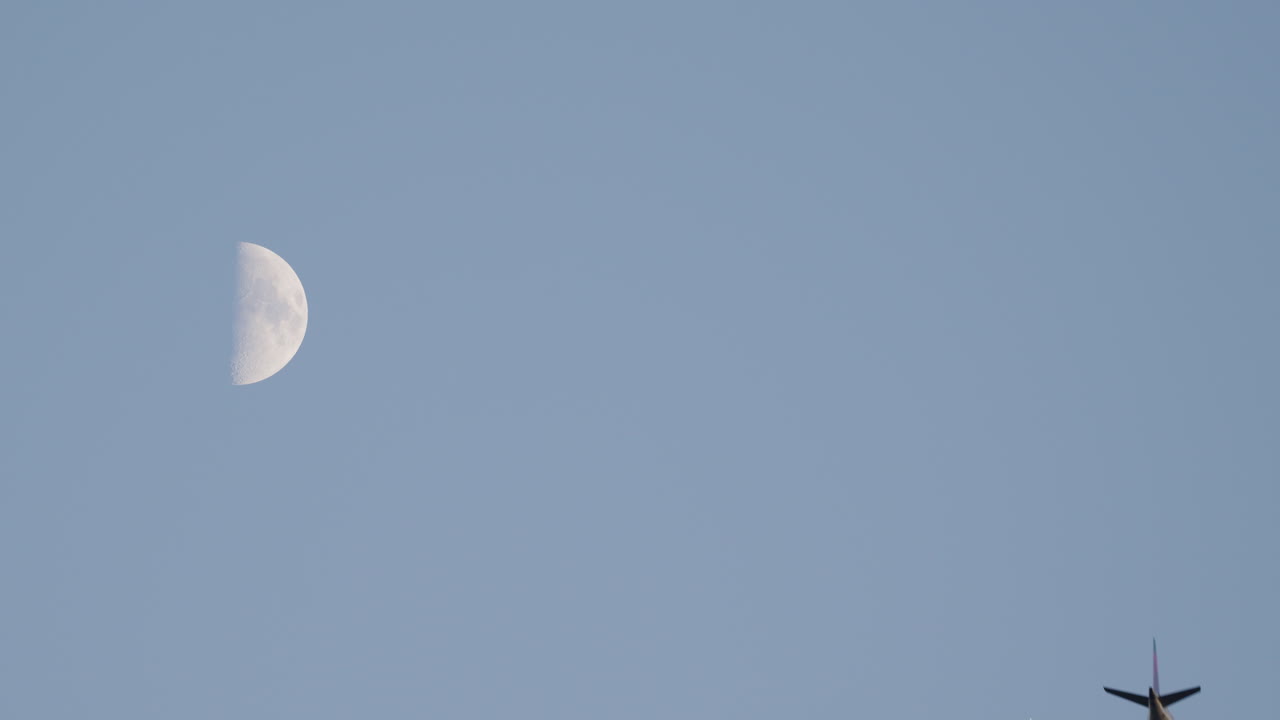 A Commercial Plane flying by the Moon during the evening. UHD 4K