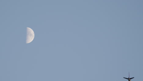 A Commercial Plane flying by the Moon during the evening. UHD 4K