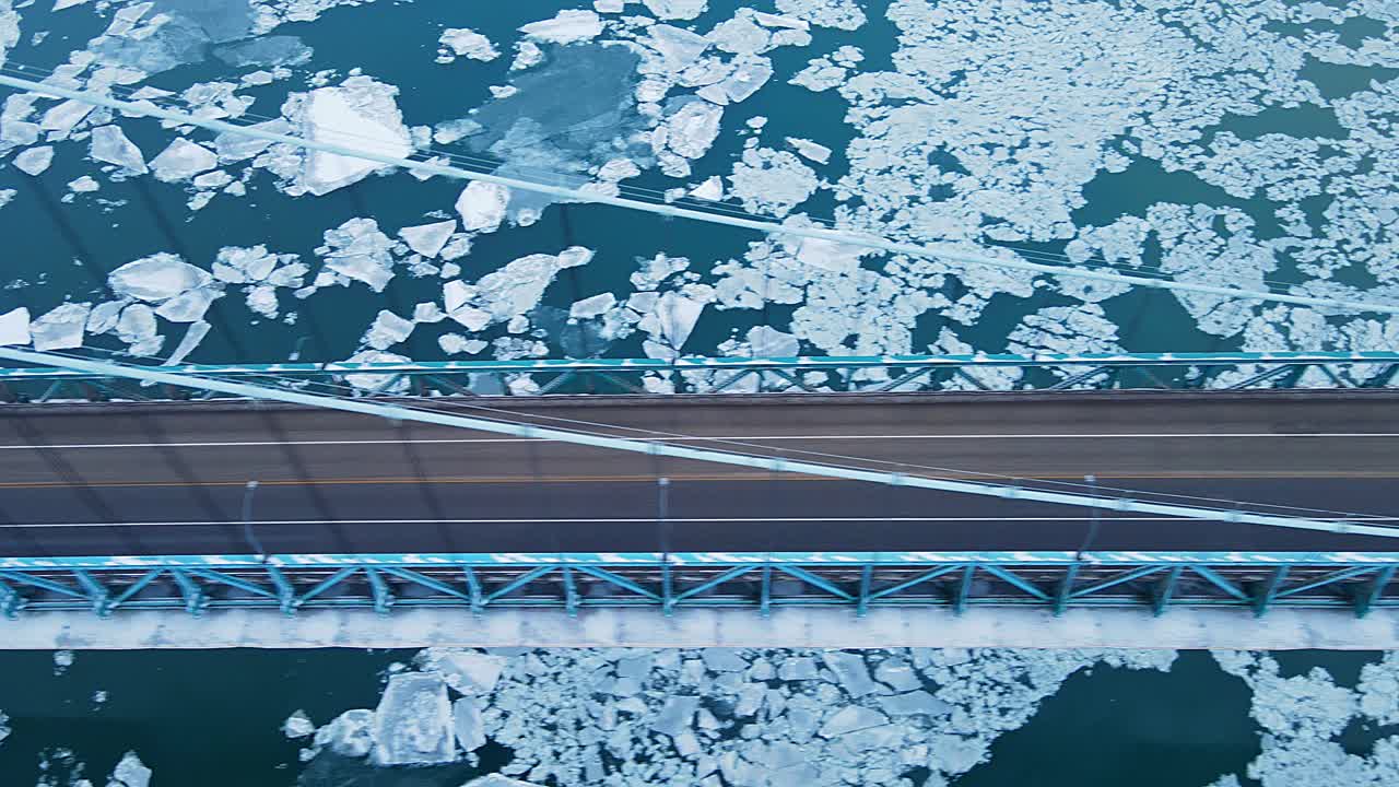Aerial downwards video of Ambassador Bridge with icy Detroit river under