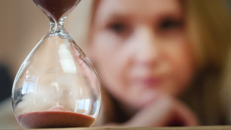 a woman looks at an hourglass 1