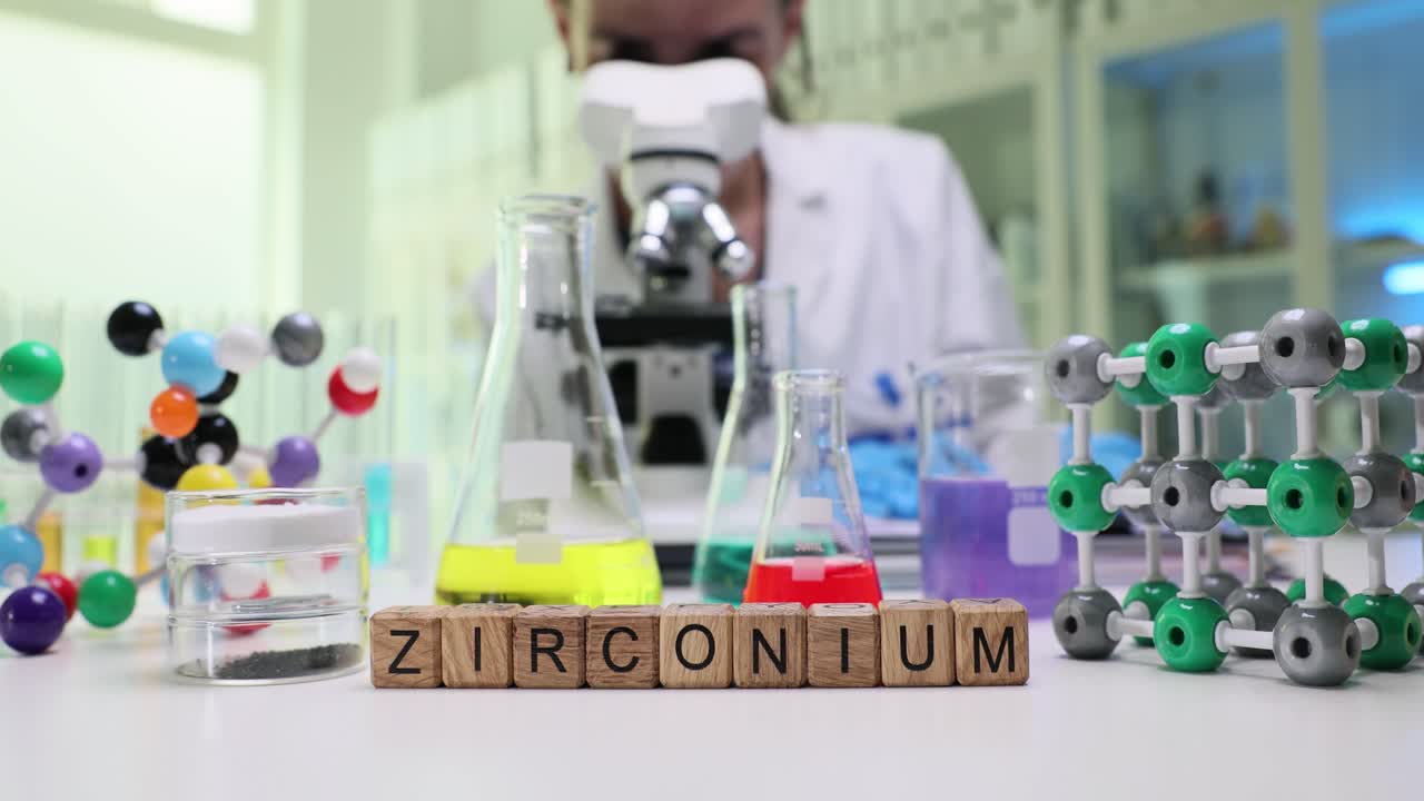 Wooden blocks spell zirconium near flasks for lab study