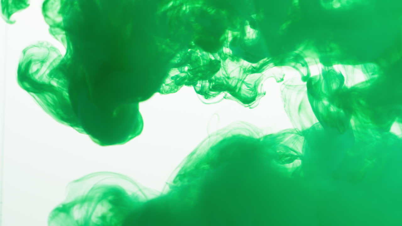 녹색 페인트 또는 염료가 색 배경에 물에 떨어지면 회전하는 다채로운 연기 배경을 만니다.