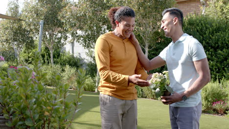 Happy-diverse-gay-male-couple-talking-in-sunny-garden,-copy-space,-slow-motion,-copy-space