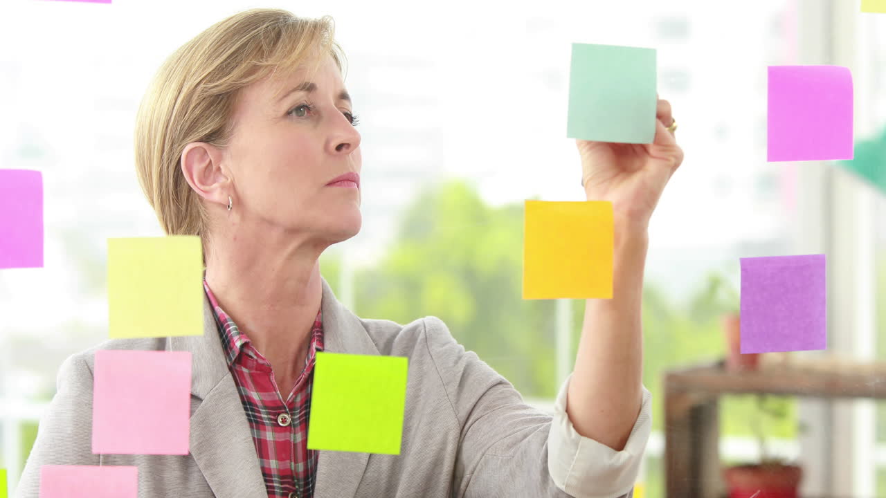 금발 디자이너가 창문에 있는 포스트를 보고 있다