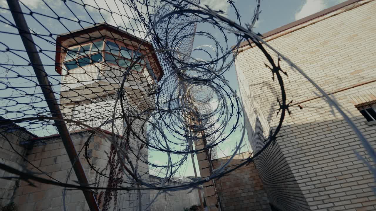 Vista con angolazione bassa di una torre di guardia di una prigione e di una recinzione di filo spinato