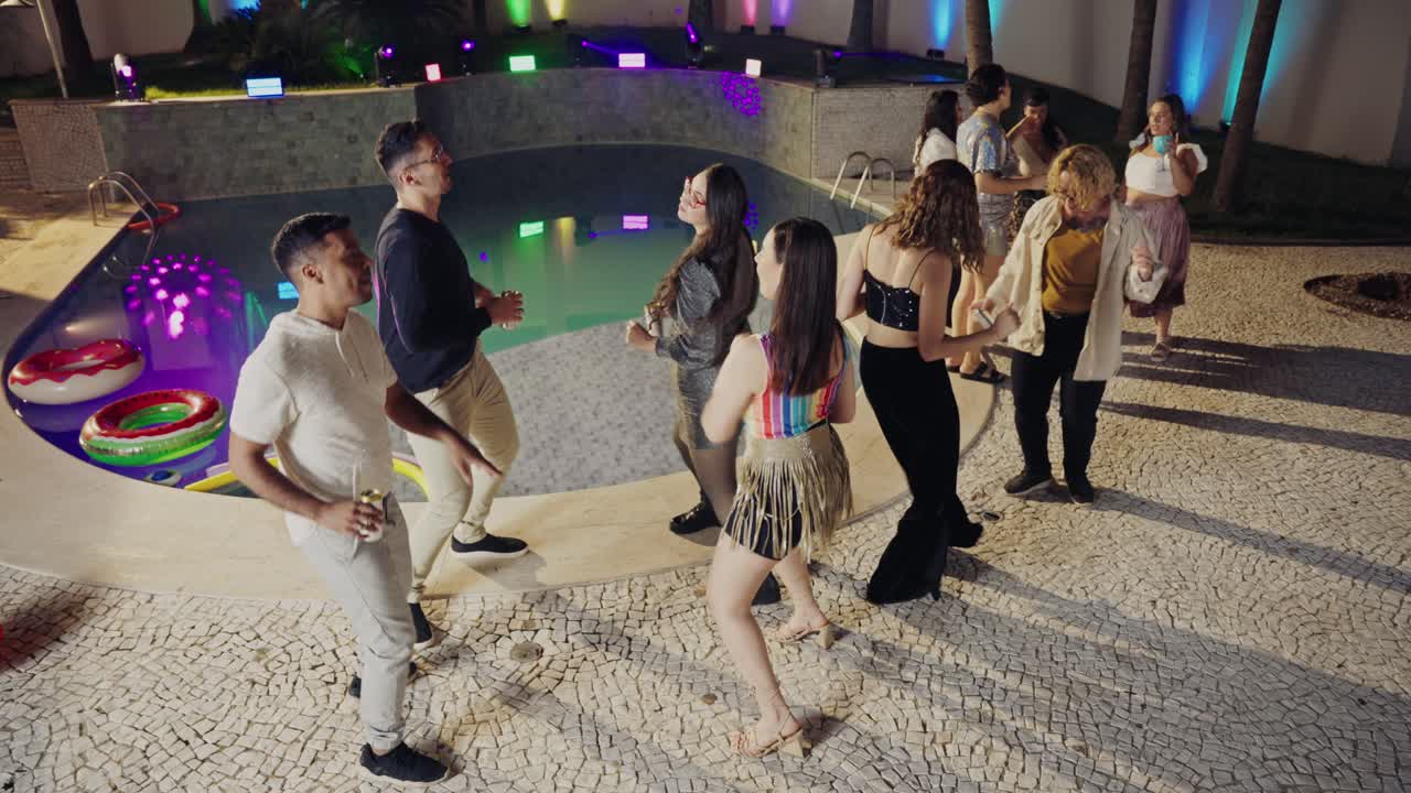 People Dancing and Socializing at a Vibrant Night Pool Party