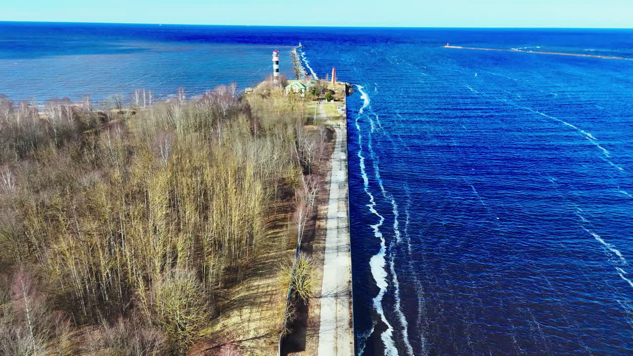 Drone view of a pier lighthouse at a river-sea confluence in Latvia