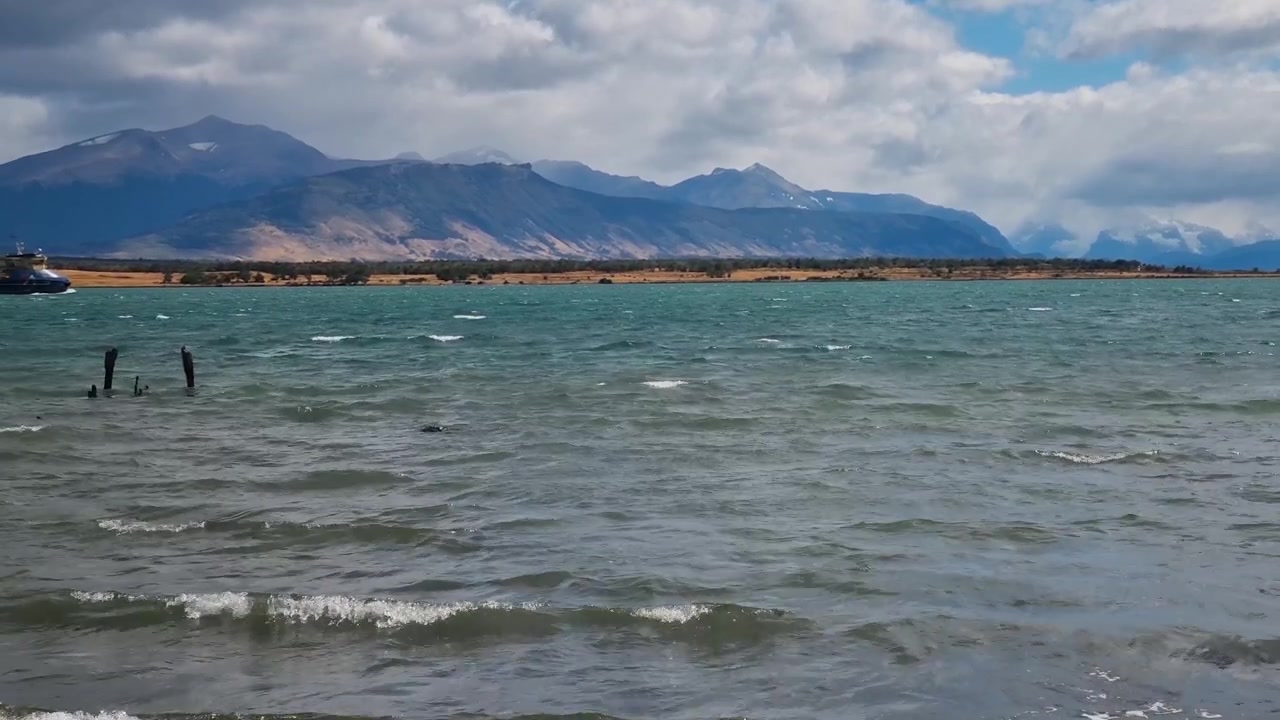 Op de wilde fjordwateren van Última Esperanza nabij Puerto Natales, Chili, beweegt een werkende baggeraar gestaag door het kanaal, omkaderd door het ruige Patagonische landschap, een alledaagse maritieme scène