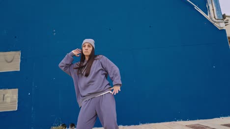 Woman in casual wear standing against a blue wall
