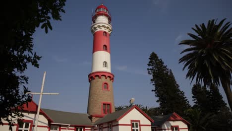 a reveal shot of the swakopmund lighthouse from behind leaves of a tree