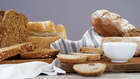 various bread loaves with butter on wooden table