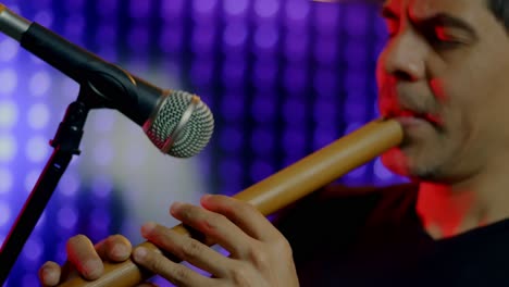 músico tocando la grabadora mientras cierra los ojos cerca del micrófono