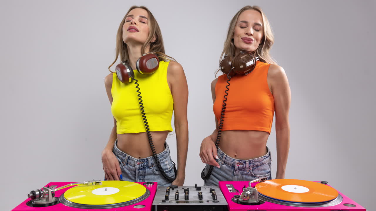 djs gemelas idénticas bailando detrás de los tocadiscos