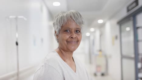 Unaltered-portrait-of-happy-biracial-female-patient-on-hospital-bed-looking-at-camera